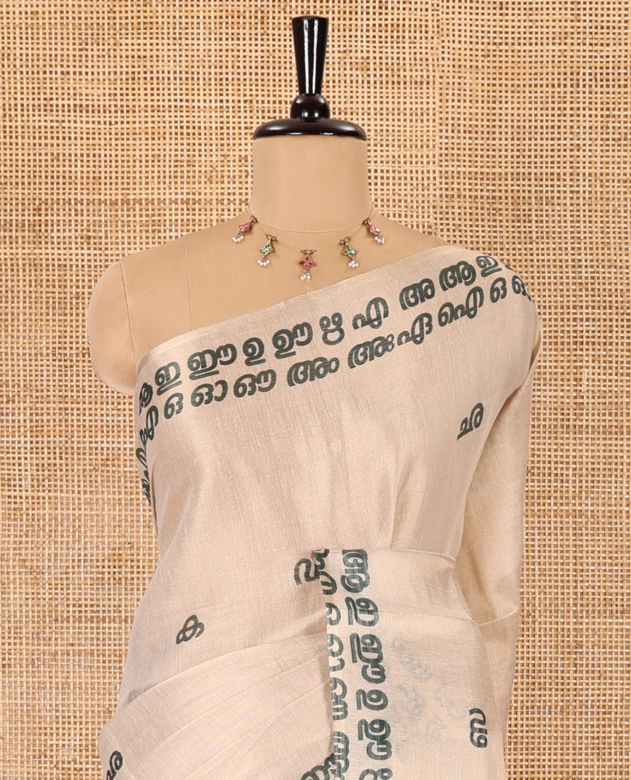 Cream-green Malayalam letter printed tissue saree, self-border and pallu steeped with Malayalam letter motifs, and a contrast plain blouse