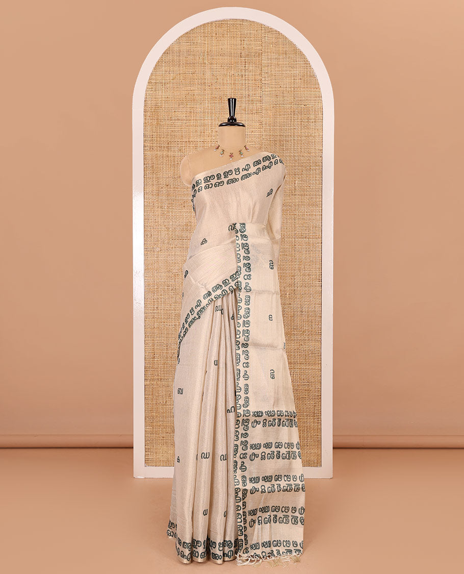 Cream-green Malayalam letter printed tissue saree, self-border and pallu steeped with Malayalam letter motifs, and a contrast plain blouse