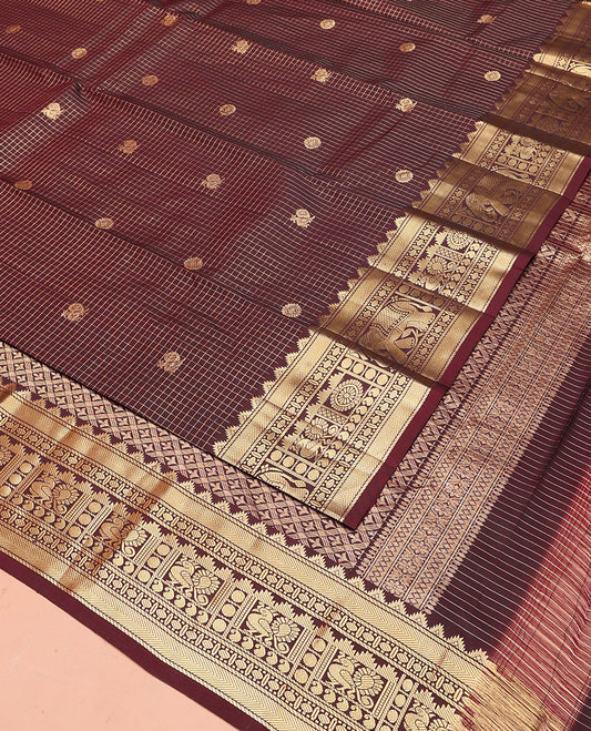 Brown Vasundhara Silk Saree Gleamed Up with Zari Checks and Annam Chakram Buttas, Complemented by a Zari Border of Thazampoo Rekku, Banaras, Paisa, Manga, and Mayil Designs, Elegantly Embellished Pallu, and Paired with a Matching Blouse