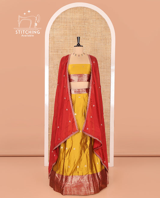 Mustard Semi-Banarasi Half-Saree, Adorned with Zari Buttas on Its Skirt, Complemented by a Contrast Traditional Zari Designs Woven Border, Paired with a Matching Blouse, and a Satin Georgette Embroidered Scallop Dhavani