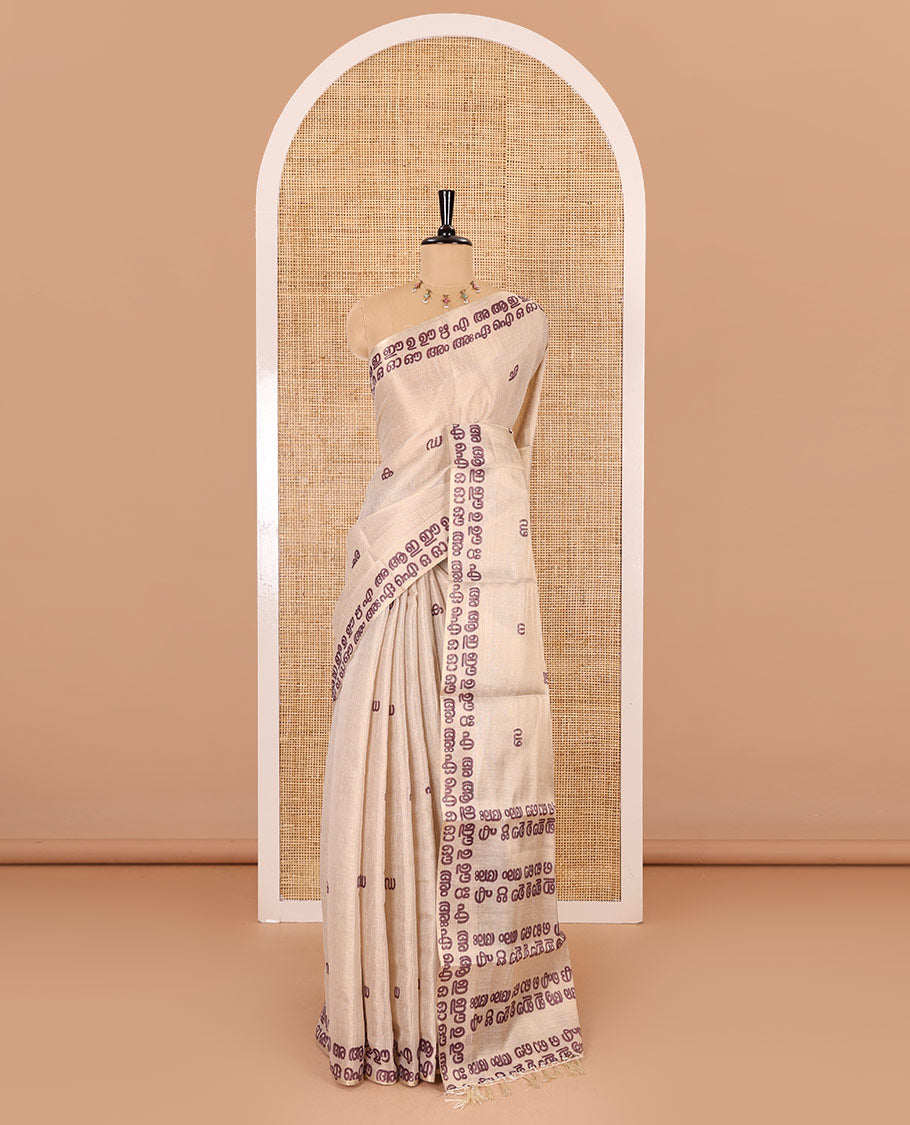 Cream-magenta Malayalam letter printed tissue saree, self-border and pallu steeped with Malayalam letter motifs, and a contrast plain blouse