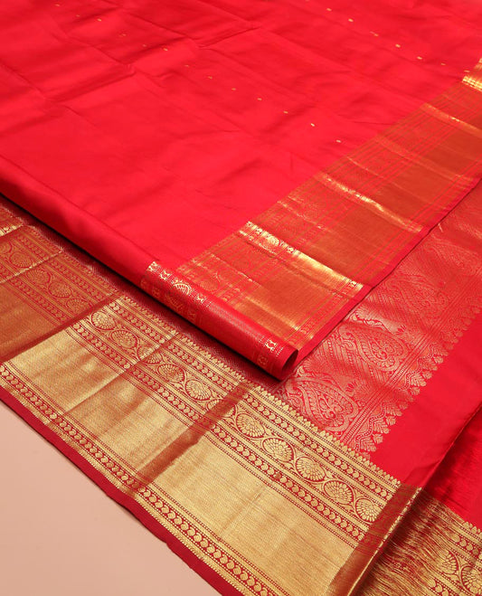 Red Kanchipuram Silk Saree, Subtly Sparkled with Zari Buttas All Over Its Body, Highlighted by a Zari Border of Thilakam, Kathir, Manga, and Dhavana Kodi Designs, Pallu of Jaal and Mayil Designs, and Paired with a Matching Blouse