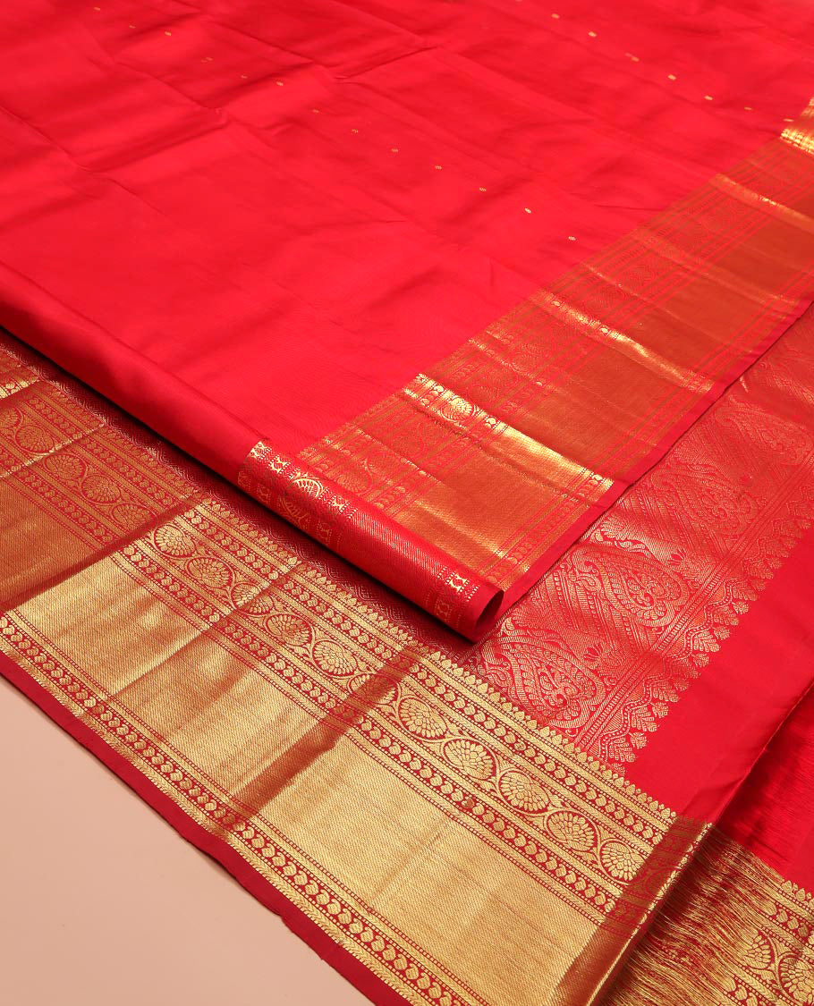 Red Kanchipuram Silk Saree, Subtly Sparkled with Zari Buttas All Over Its Body, Highlighted by a Zari Border of Thilakam, Kathir, Manga, and Dhavana Kodi Designs, Pallu of Jaal and Mayil Designs, and Paired with a Matching Blouse
