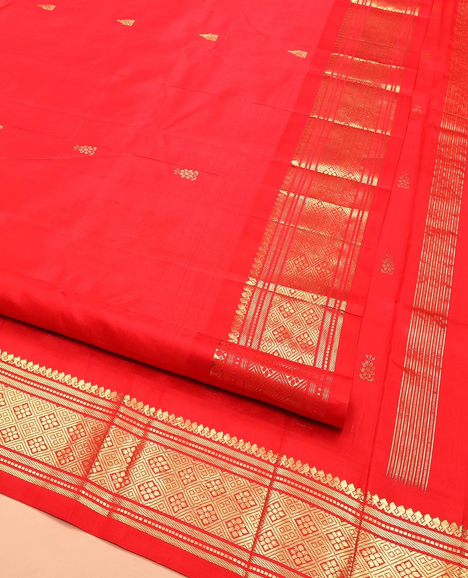 Red Kanchipuram Silk Saree Spotlighted with Zari Buttas All Over Its Body, Highlighted by Zari One-sided Border Featuring Thilakam Mokku, Banaras, Muthu, and Jaal Designs, Zari Design Pallu, and Comes Without a Blouse
