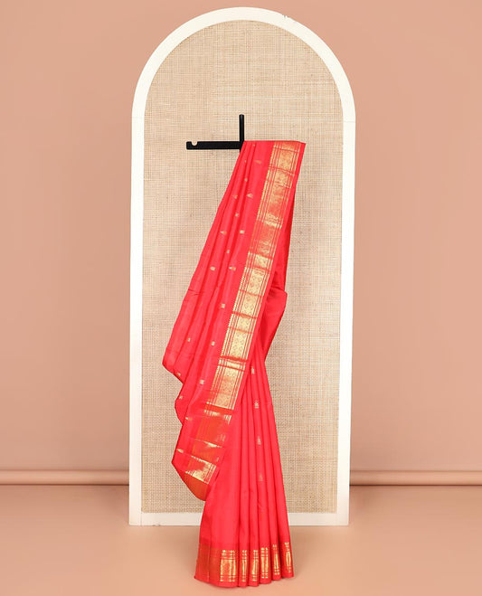 Red Kanchipuram Silk Saree Spotlighted with Zari Buttas All Over Its Body, Highlighted by Zari One-sided Border Featuring Thilakam Mokku, Banaras, Muthu, and Jaal Designs, Zari Design Pallu, and Comes Without a Blouse