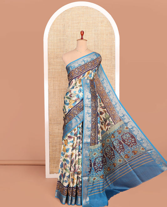 Cream and Blue Semi-Tussar Saree Enthralled with Colorful Floral Vine Print, Complemented by a Contrast Zari Border, Pallu Featuring Ikkat Design Print, and Paired with a Contrast Blouse