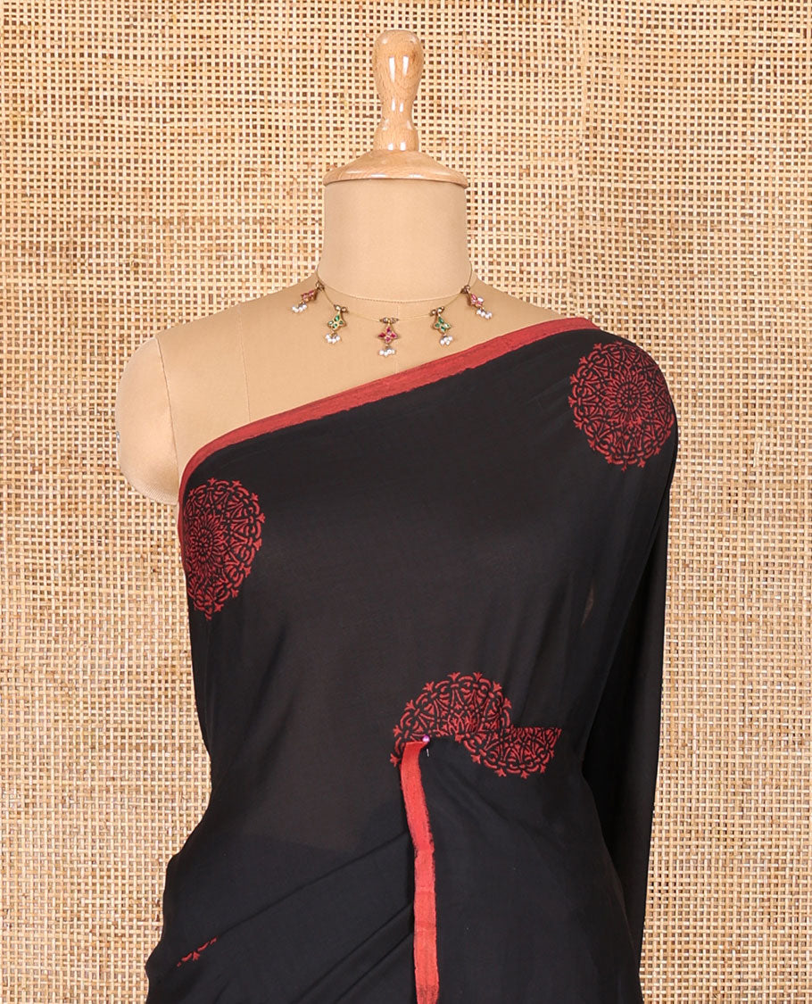 Borderless black rangoli-style chakram motifs printed South cotton saree with a matching blouse, and a contrast floral printed blouse