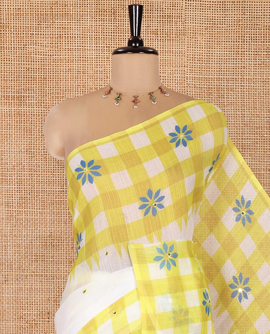 White and Green Linen Cotton Saree, Adorned with Mirror Work On Its Body, Complemented by Contrast Temple Checked Border of Floral Print and Mirror Work, Pallu Mirrors the Same Design and Paired with a Contrast Blouse
