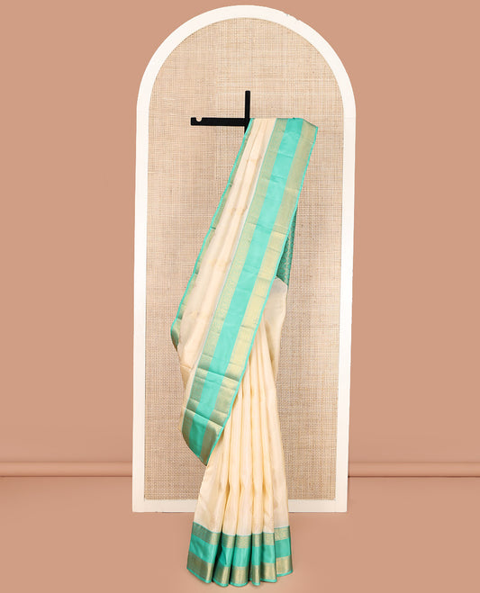 Cream Vasundhara Lite Silk Mix Saree, Gracefully Embellished with Zari Buttas All Over Its Body, Complemented by a Contrast Rettai Pettu Border of Thilakam Mokku, Kodi Visiry, and Kamalam Designs, Grand Jaal Design Pallu, and Paired with a Contrast Blouse