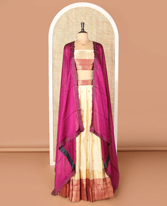 Cream-magenta art-silk half-saree, zari buttas with contrast traditional design bordered skirt, a matching blouse, and scallop stone work dhavani