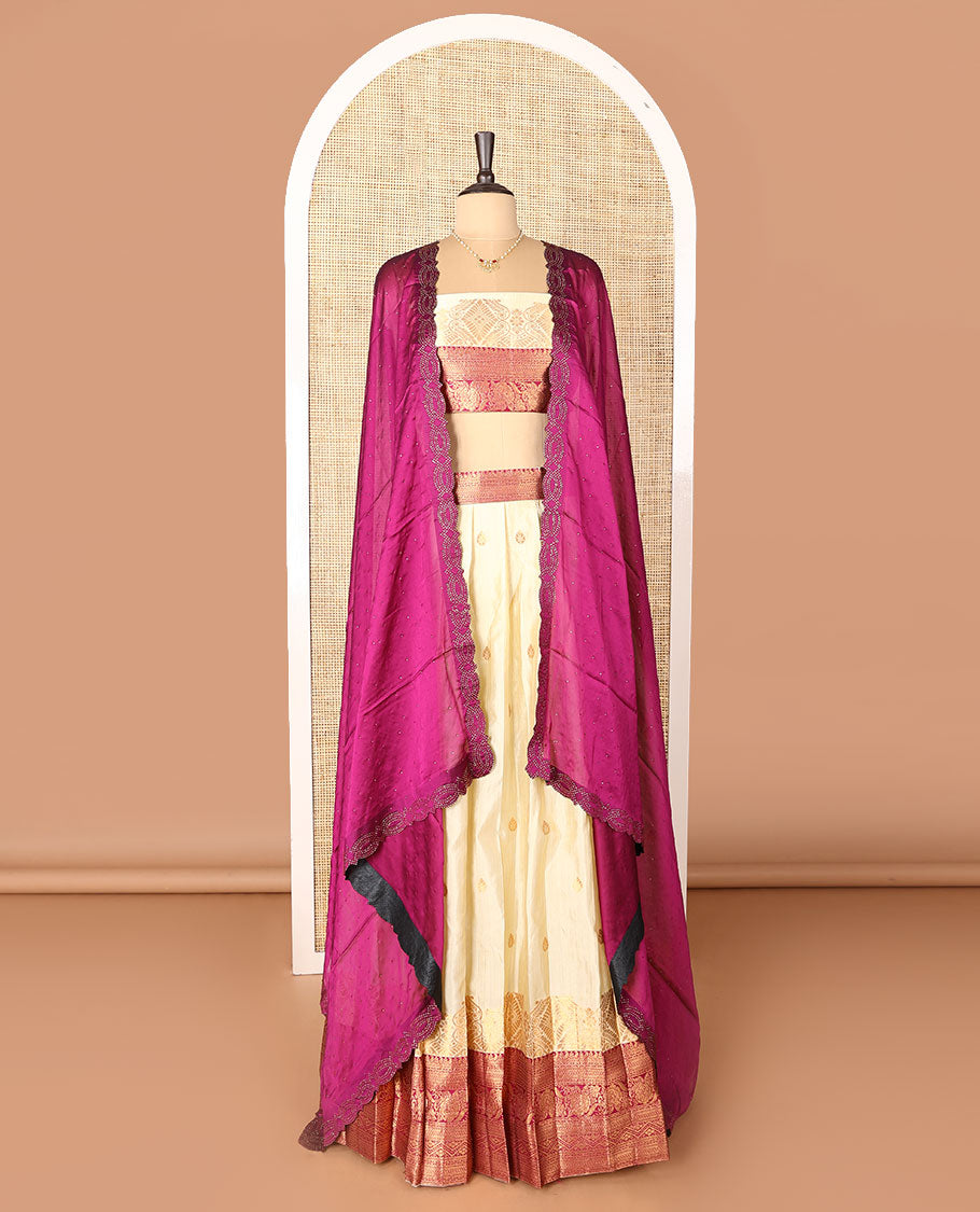 Cream-magenta art-silk half-saree, zari buttas with contrast traditional design bordered skirt, a matching blouse, and scallop stone work dhavani