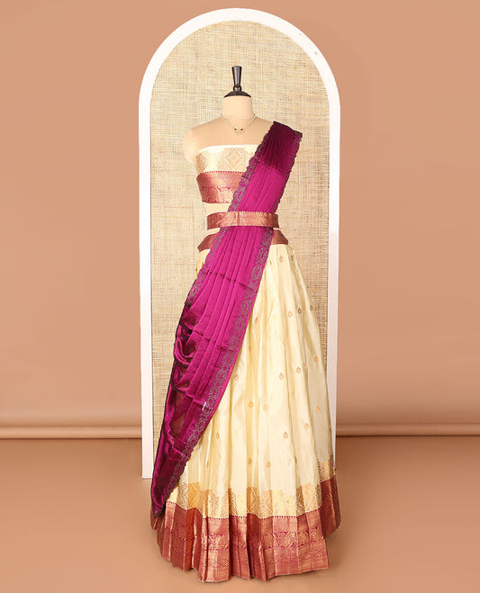 Cream-magenta art-silk half-saree, zari buttas with contrast traditional design bordered skirt, a matching blouse, and scallop stone work dhavani