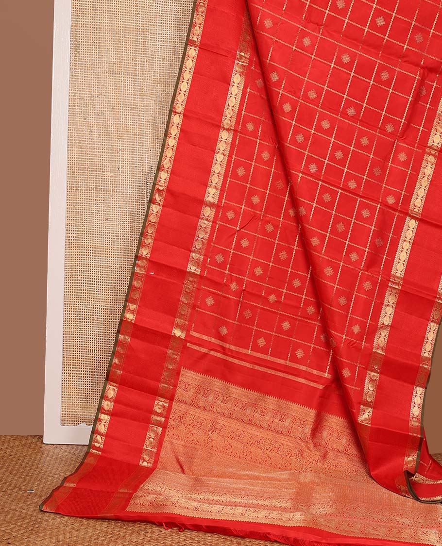 Red kolam buttas enclosed neli checked Kanchipuram silk saree, zari border of thilakam, kathir, and rudraksham designs, and pallu of neli, Greek key, yaanai, and mayil design