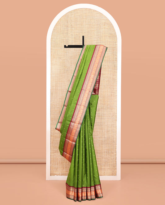 Green Vasundhara Silk Saree, Sparsely Woven with Zari Buttas All Over Its Body, Complemented by a Contrast Border of Rekku, Poun, Kathir, and Mayil Designs, Pallu Steeped with the Same Border Designs, and Paired with a Contrast Blouse