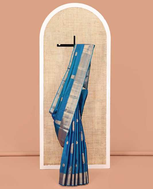 Blue Vasundhara Lite Silk Saree, Accentuated with Zari Buttas All Over Its Body, Highlighted by Zari Border of Thilakam, Mayil Kann, Kamalam, Rettai Neli, Yannai, and Vanki Designs, Delicately Woven Pallu and Paired with a Matching Blouse