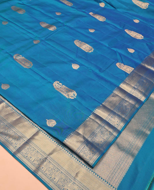 Blue Vasundhara Lite Silk Saree, Accentuated with Zari Buttas All Over Its Body, Highlighted by Zari Border of Thilakam, Mayil Kann, Kamalam, Rettai Neli, Yannai, and Vanki Designs, Delicately Woven Pallu and Paired with a Matching Blouse