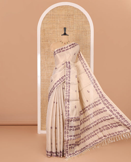 Cream-magenta Malayalam letter printed tissue saree, self-border and pallu steeped with Malayalam letter motifs, and a contrast plain blouse