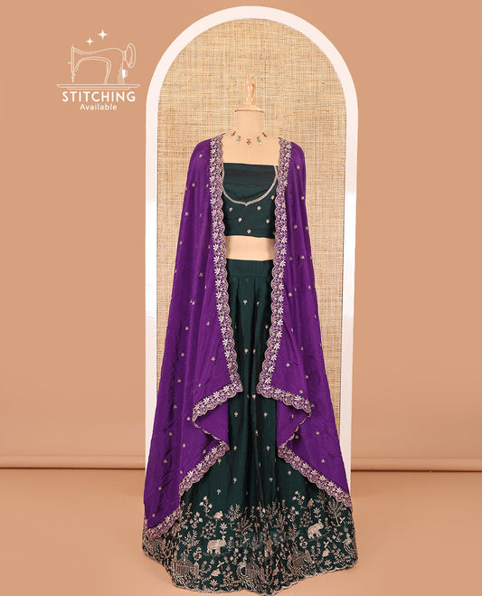 Bottle green half-saree, buttas and flora-fauna embroidered bordered velvet organza skirt, a matching velvet organza blouse, and a contrast embroidered scallop syska georgette dhavani