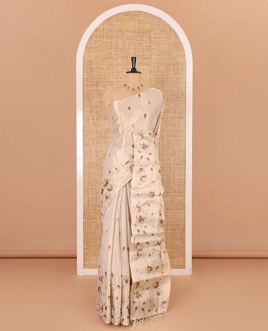 Cream leaf and floral printed tissue saree with border and pallu of floral and leaf print, a small floral printed blouse