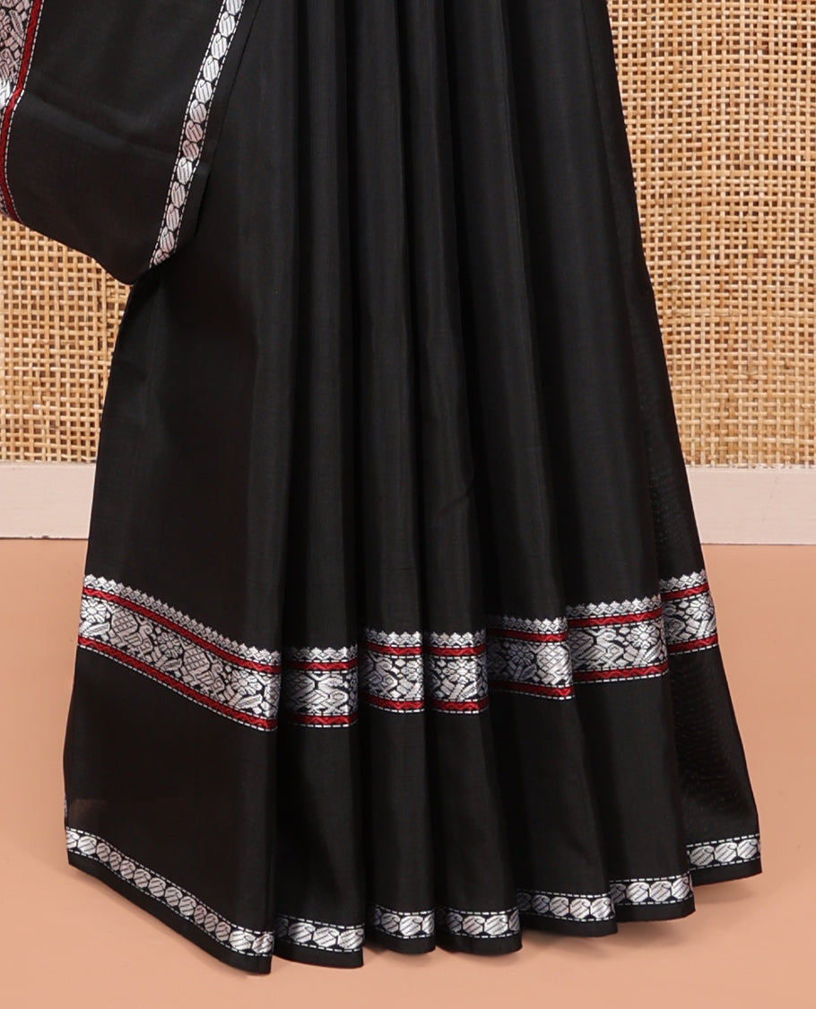 Black Kanchipuram Silk Saree, Delicately Woven with Buttas All Over Its Body, Highlighted by a Rettai Pettu Border of Thilakam Mokku, Neli, Mayil, and Manga Designs, Pallu Steeped with Stripes, and Paired with a Matching Blouse