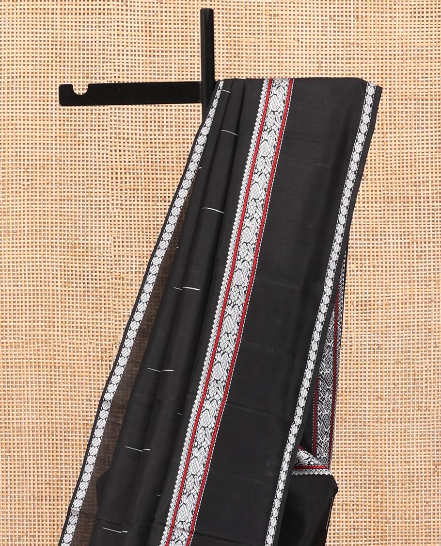 Black Kanchipuram Silk Saree, Delicately Woven with Buttas All Over Its Body, Highlighted by a Rettai Pettu Border of Thilakam Mokku, Neli, Mayil, and Manga Designs, Pallu Steeped with Stripes, and Paired with a Matching Blouse