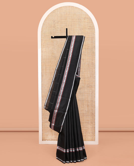 Black Kanchipuram Silk Saree, Delicately Woven with Buttas All Over Its Body, Highlighted by a Rettai Pettu Border of Thilakam Mokku, Neli, Mayil, and Manga Designs, Pallu Steeped with Stripes, and Paired with a Matching Blouse
