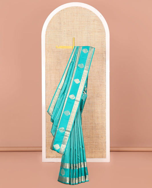 Blue Vasundhara Silk Saree Decked Up with Zari Buttas All Over Its Body, Highlighted by a Zari Border of Thilakam Mokku, Poun, Mayil, and Zari Designs, Grand Pallu of Butta Enclosed Checks, and Paired with a Matching Blouse