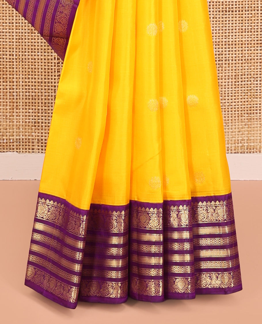 Yellow Vasundhara Silk Saree, Sparsely Woven with Zari Buttas All Over Its Body, Complemented by a Contrast Border of Thilakam, Muthu, Mayil, and Mayil Kann Designs, Pallu of Zari Designs, and Paired with a Contrast Blouse