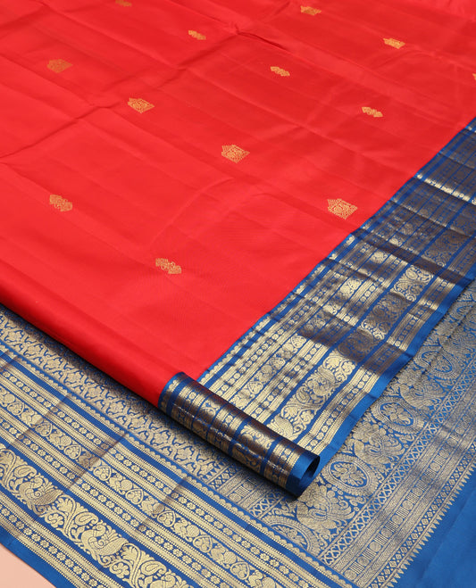 Red Vasundhara Silk Saree, Subtly Sparkled With Zari Buttas All Over Its Body, Complemented by Contrast Border of Salngai, Muthu, Kamalam, Jada Nagam, and Mayil Designs, Grand Pallu and Paired with a Contrast Blouse