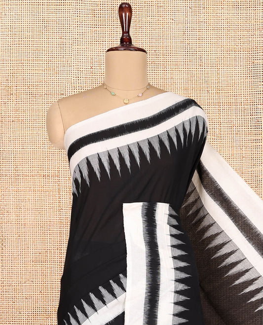 Black Plain Ikkat Cotton Saree, Complemented by a Contrast Ikkat Temple Border, Pallu Steeped with Buttas, and Paired with a Contrast Blouse