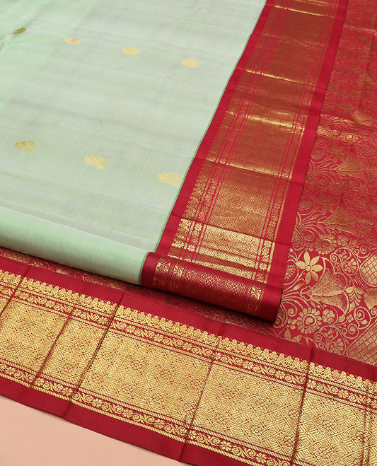 Green Kanchipuram Silk Saree Ornamented with Zari Buttas All Over Its Body, Complemented by Contrast One-Sided Border of Jaal Designs, Grandly Woven Pallu of Floral Designs, and Comes Without a Blouse