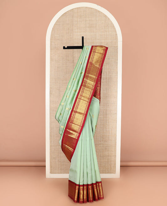 Green Kanchipuram Silk Saree Ornamented with Zari Buttas All Over Its Body, Complemented by Contrast One-Sided Border of Jaal Designs, Grandly Woven Pallu of Floral Designs, and Comes Without a Blouse