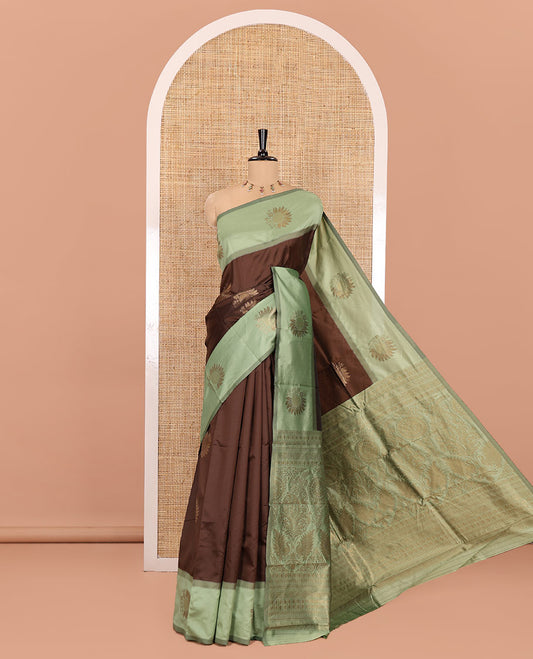 Brown Kanchi Silk Saree, Adorned with Zari Buttas All Over Its Body, Complemented by a Contrast Border of Flower Motifs, Pallu Features Intricate Designs, and Paired with a Contrast Blouse