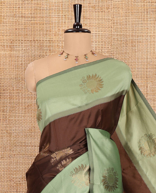 Brown Kanchi Silk Saree, Adorned with Zari Buttas All Over Its Body, Complemented by a Contrast Border of Flower Motifs, Pallu Features Intricate Designs, and Paired with a Contrast Blouse