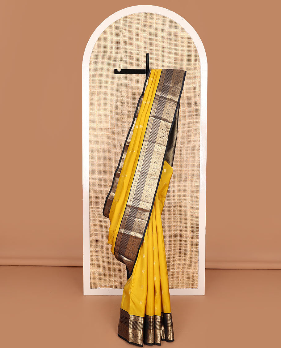 Yellow Vasundhara Lite-Silk Mix Saree Decked Up with Zari Buttas, Complemented by a Contrast Black Border Depicting Manga, Muthu, Kamalam, Banaras, Diamond, and Mayil Designs, Pallu Steeped with Diagonal Leaf Vines, and a Contrast Blouse
