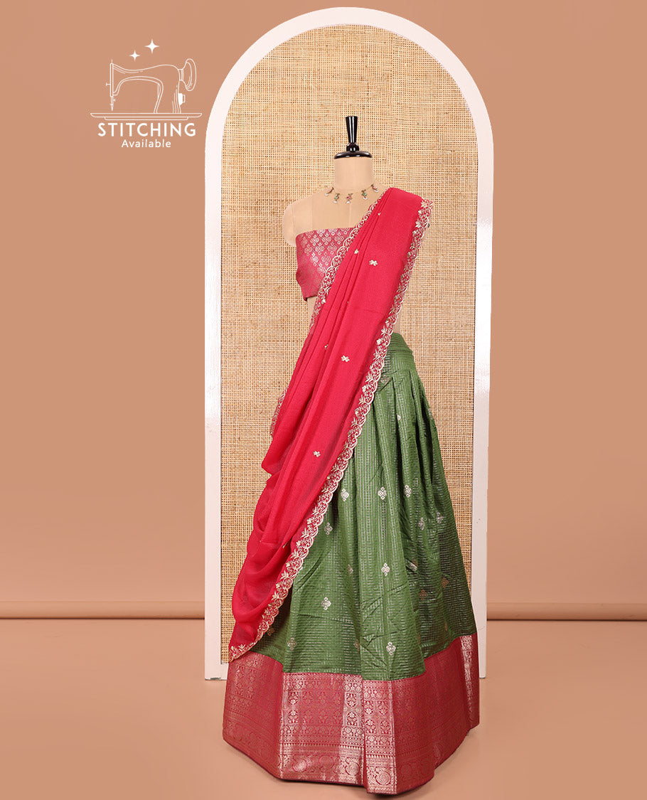 Green and Red Banaras Silk Half-Saree Featuring Zari Checks and Zari Buttas All Over the Skirt, Complemented by Contrast Traditional Zari Design Border, Paired with a Jacquard Blouse, and a Rangoli Georgette Dhavani of Embroidery and Scallop Border