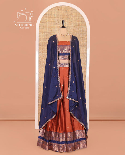 Rust and Blue Semi-Banarasi Half-Saree Featuring Zari Buttas Skirt, Complemented by Contrast Rettai Pettu, Traditional Border of Floral Creeper Designs, Paired with a Matching Blouse, and a Satin Georgette Embroidered Scallop Dhavani