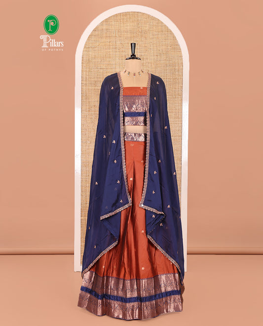 Rust and Blue Semi-Banarasi Half-Saree Featuring Zari Buttas Skirt, Complemented by Contrast Rettai Pettu, Traditional Border of Floral Creeper Designs, Paired with a Matching Blouse, and a Satin Georgette Embroidered Scallop Dhavani