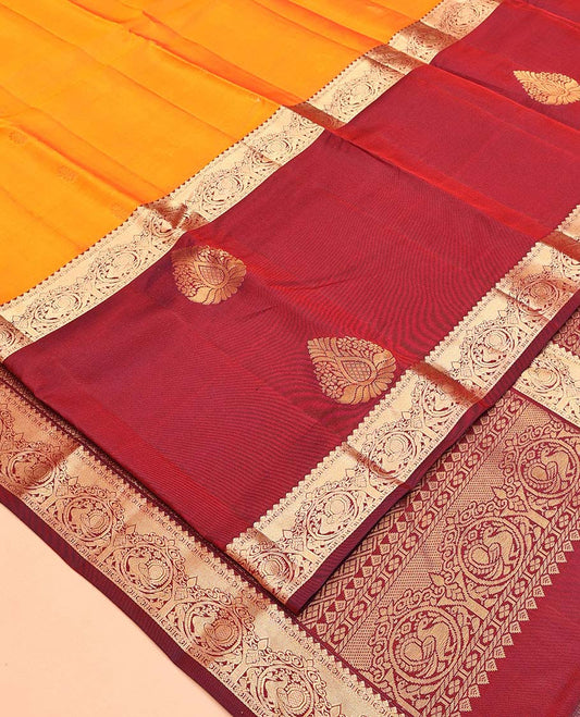 Orange Vasundhara Lite Silk Mix Saree, Subtly Sparkled with Zari Buttas All Over Its Body, Complemented by a Contrast Border of Thilakam, Kamalam, and Round Mayil Designs, Intricately Designed Pallu, and Paired with a Contrast Blouse