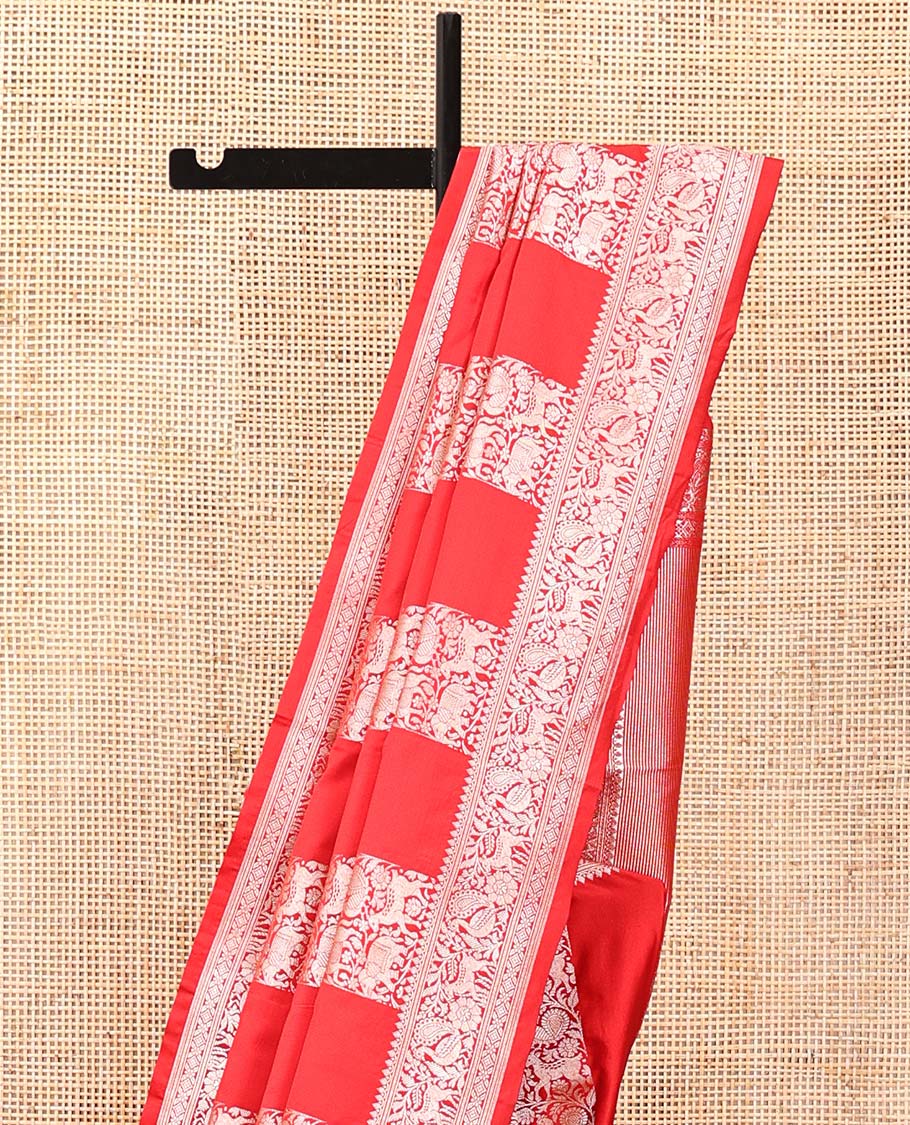 Red Mushuru Silk Saree, Gracefully Embellished with Vertically Woven Flora-Fauna Zari Designs On Its Body, Highlighted by Zari Border of Peacock and Deer Motifs, Grand Pallu, and Paired with a Plain Blouse