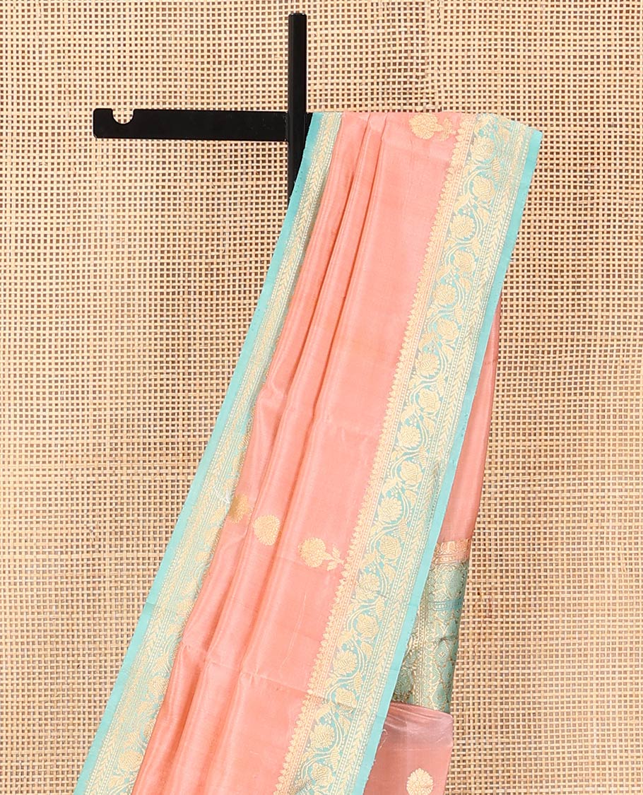 Peach Raw Mango Silk Saree Bedecked with Buttas, Features a Contrast floral creeper design Border, adorned with intricately designed Pallu, and comes with a Contrast Blouse