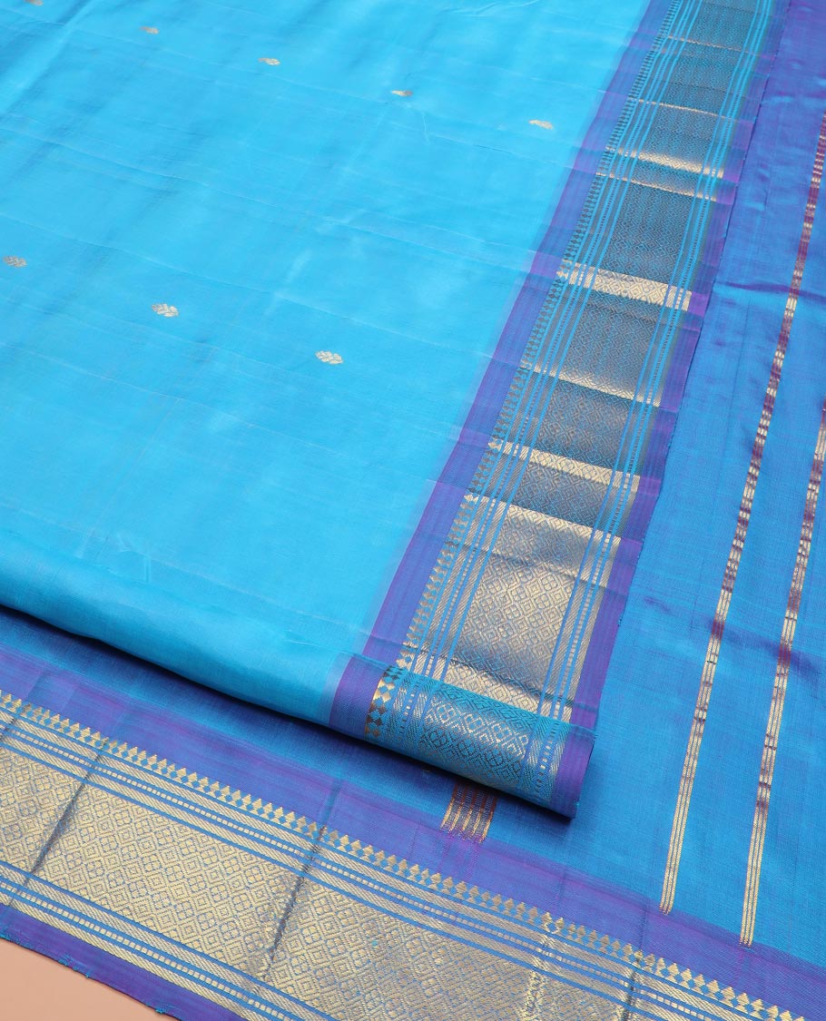 Blue Kanchipuram Silk Saree Enthralled with Zari Buttas All Over Its Body, Complemented by a Contrast One-Sided Border of Paneer Sombu, Banaras, Muthu, and Jaal Designs, Zari Design Pallu, and Comes Without a Blouse
