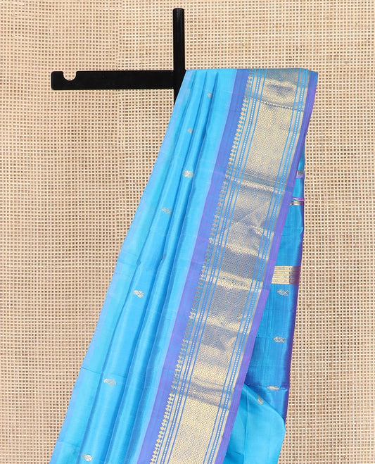 Blue Kanchipuram Silk Saree Enthralled with Zari Buttas All Over Its Body, Complemented by a Contrast One-Sided Border of Paneer Sombu, Banaras, Muthu, and Jaal Designs, Zari Design Pallu, and Comes Without a Blouse