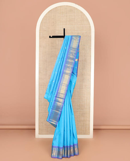Blue Kanchipuram Silk Saree Enthralled with Zari Buttas All Over Its Body, Complemented by a Contrast One-Sided Border of Paneer Sombu, Banaras, Muthu, and Jaal Designs, Zari Design Pallu, and Comes Without a Blouse