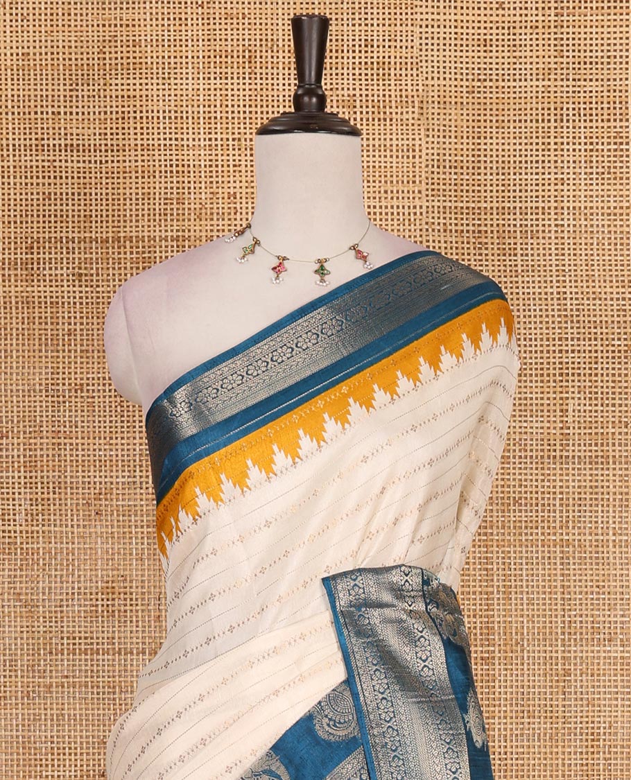 Half-white zari designs dola silk saree, contrast blue temple traditional border of peacock and elephant motifs, and temple pallu