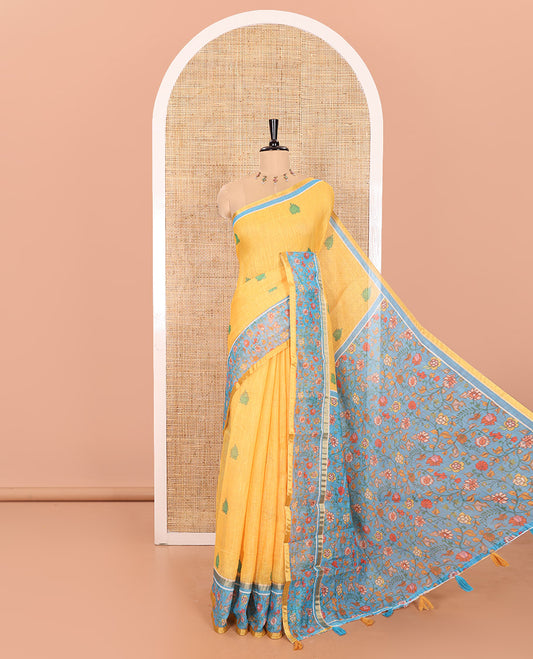 Yellow Linen Saree Detailed with Leaf Motifs All Over Its Body, Complemented by a Contrast Floral Vine Printed Border, Pallu Mirrors the Floral Vine Print, and Paired with a  Contrast Floral Printed Blouse
