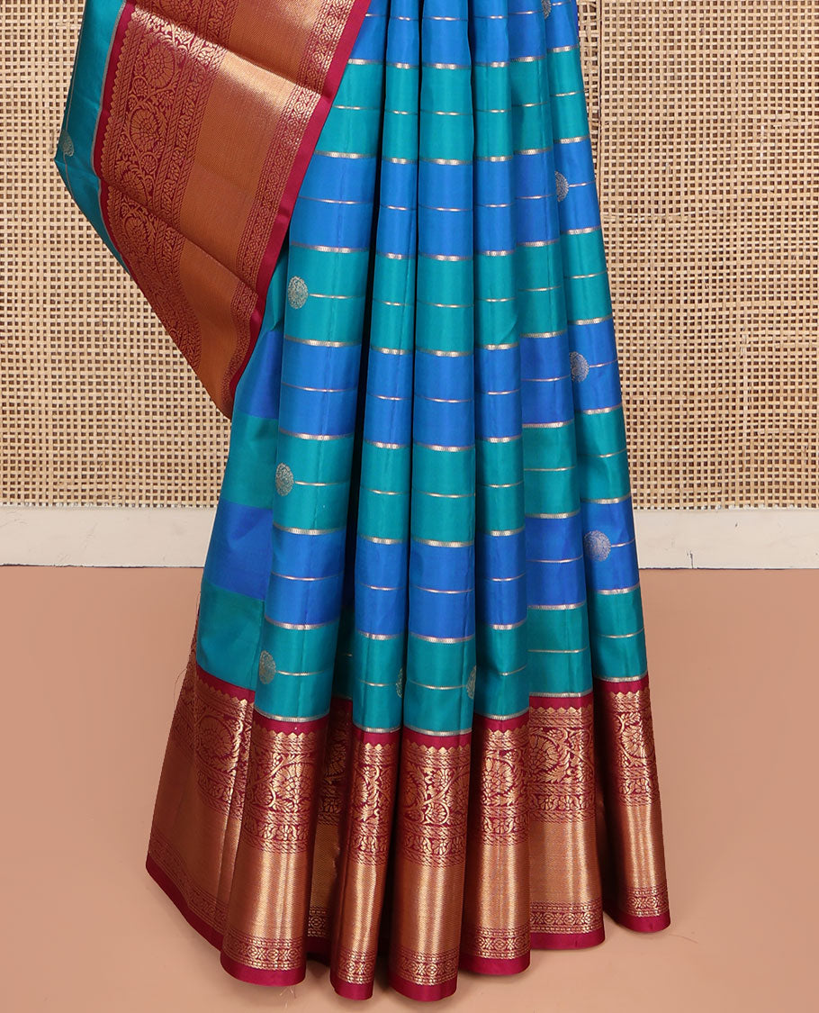 Blue Vasundhara Silk Saree, Impeccably Styled with Zari Buttas and Zari Stripes All Over Its Body, Complemented by a Contrast Border of Salngai, Puli Nagam, and Kodi Visiry Designs, Grand Gleaming Zari Woven Pallu, and Paired with a Contrast Blouse