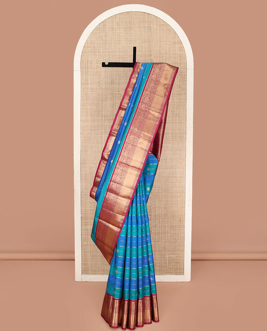 Blue Vasundhara Silk Saree, Impeccably Styled with Zari Buttas and Zari Stripes All Over Its Body, Complemented by a Contrast Border of Salngai, Puli Nagam, and Kodi Visiry Designs, Grand Gleaming Zari Woven Pallu, and Paired with a Contrast Blouse