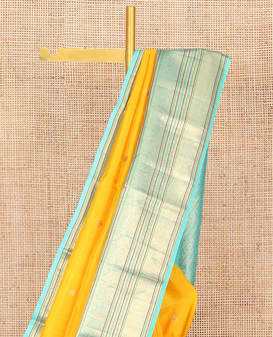 Yellow Vasundhara Silk Saree Decorated with Zari Buttas All Over Its Body, Complemented by a Contrast Border of Leaf, Rudraksham, Diamond, and Mayil Kann Designs, Pallu Featuring Manga Creeper Designs, and Paired with a Contrast Blouse