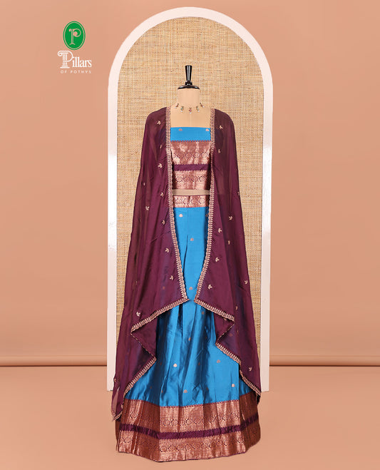 Blue and Purple Semi-Banarasi Half-Saree Featuring Zari Buttas Skirt, Complemented by Contrast Rettai Pettu, Traditional Border of Floral Creeper Designs, Paired with a Matching Blouse, and a Satin Georgette Embroidered Scallop Dhavani